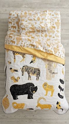 a white bed with yellow and black animal print on the comforter, next to a wooden floor