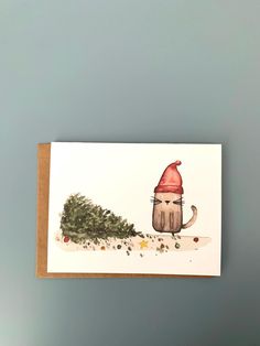 a card with an image of a cat wearing a santa hat and holding a christmas tree