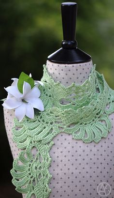 a white flower is on top of a green shawl with polka dots and lace