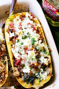 two stuffed squash boats with meat, cheese and sauce in a casserole dish