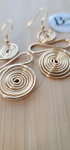 two pairs of earrings sitting on top of a wooden table