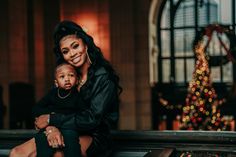 a woman and child sitting on a bench in front of a christmas tree