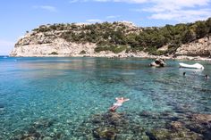 people swimming in clear blue water near an island