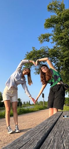 two young women standing on top of a wooden bench