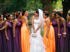 a group of women standing next to each other wearing purple and orange bridesmaid dresses