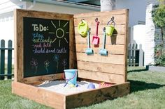 an outdoor sandbox with chalkboard and magnets attached to it in front of a house