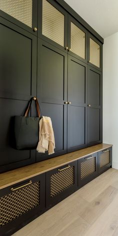 a large black coat rack sitting on top of a wooden floor next to a purse