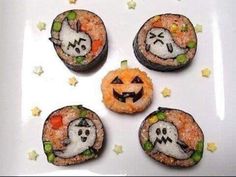 four sushi rolls decorated with halloween faces and ghost faces on them, sitting on a white plate