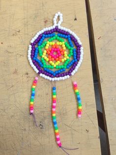 a colorful beaded dream catcher sitting on top of a wooden table