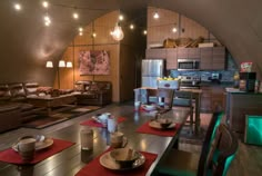 a living room filled with furniture and lots of lights hanging from the ceiling next to a kitchen