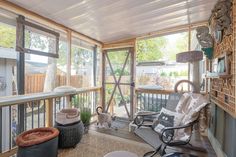 a screened porch with lots of windows and furniture on the outside, including two rocking chairs