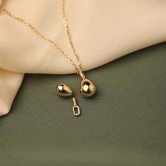 a gold necklace and earring laying on top of a white cloth next to a pair of scissors