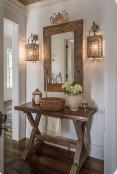 a wooden table topped with a vase filled with flowers next to a mirror and lights