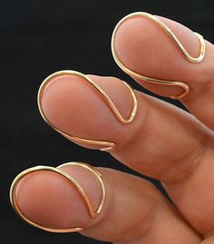 a woman's hand with two gold rings on her fingers and one ring in the middle