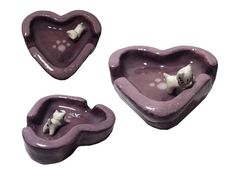 three purple heart shaped dishes with cats on them