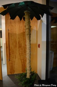 a tall palm tree sitting in front of a doorway next to a planter with leaves on it