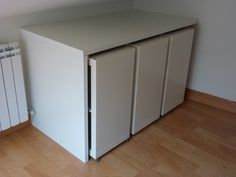 a white cabinet sitting on top of a hard wood floor next to a radiator