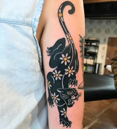 a person with a tattoo on their arm that has a black cat and flowers on it