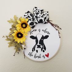 a white wall with a black and white cow, sunflowers and some words on it