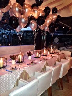 a long table is set with black and silver balloons, white linens, and candles