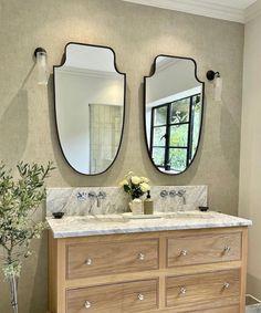 a bathroom with two mirrors on the wall and a wooden dresser in front of it