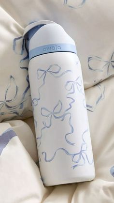 a white and blue water bottle sitting on top of a bed covered in sheets with bows