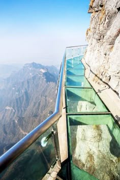 the glass walkway on top of a mountain is very high in the air and looks like it's going down