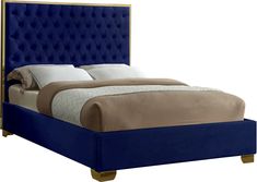 a bed with blue upholstered headboard and beige pillows on top of it