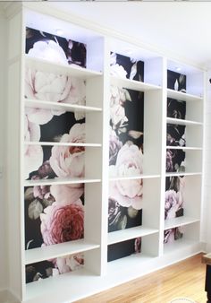 a white bookcase with flowers painted on the front and back sides, along with a wooden table