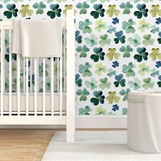 a white crib in front of a wall with green and blue flowers on it