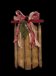 a wooden sled with a red and white bow hanging from it's side