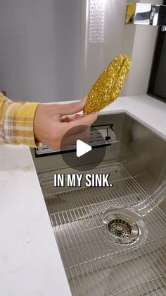 a person is cleaning a sink with gold colored sponges on the bottom of it