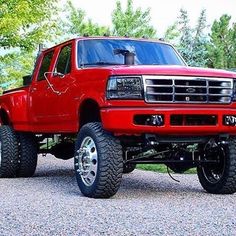 a red pick up truck parked on top of a gravel road