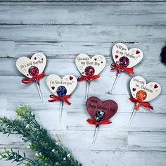 four heart shaped lollipops with red bows on them and some flowers in the background