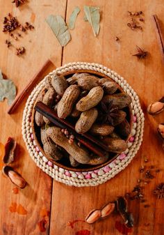 a bowl filled with nuts and cinnamons on top of a wooden table next to leaves