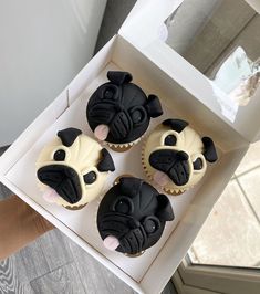 three cupcakes with black and white frosting in a box