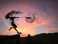 a woman is holding a dandelion in the air with her arms and legs