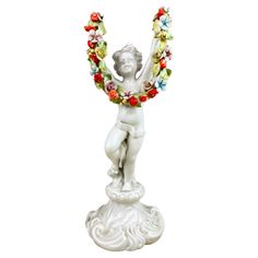 a white statue with flowers around it's neck and hands in the shape of a woman