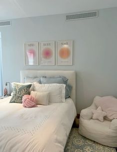 a white bed sitting in a bedroom next to a window filled with lots of pillows