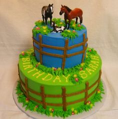 a birthday cake decorated with horses on the top and fenced in grass around it