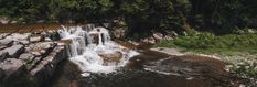 there is a waterfall in the middle of some rocks and water with trees around it