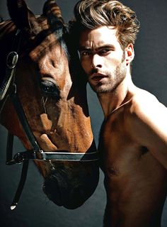 a shirtless man standing next to a horse