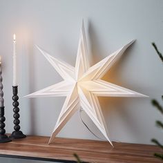 an origami star is sitting on a mantle next to candles and a candle holder