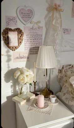 a white table topped with a lamp next to a vase filled with flowers and candles