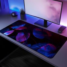 a desk with a computer monitor, mouse and cell phone on it next to a plant