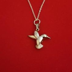 a silver bird necklace on a red background