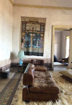 a living room with couches and rugs in front of a painting on the wall