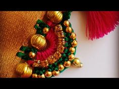 a close up view of some gold and green beads on a red pillow with tassels