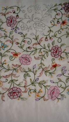 an embroidered tablecloth with flowers and vines on white fabric, closeup view from the bottom