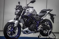 a silver and black motorcycle parked in front of a garage door on a blue carpet